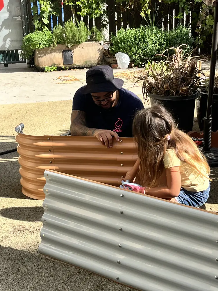 A volunteer and a young helper assembling a new raised garden bed
